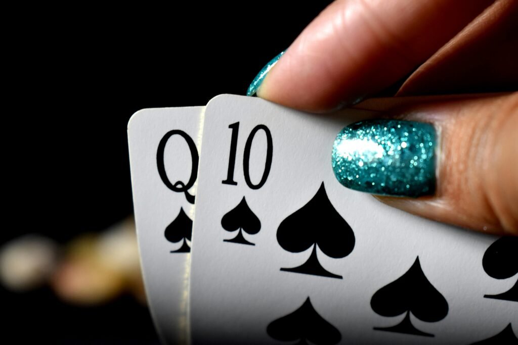 Intense close-up of a hand holding Queen and Ten of spades in a poker game.